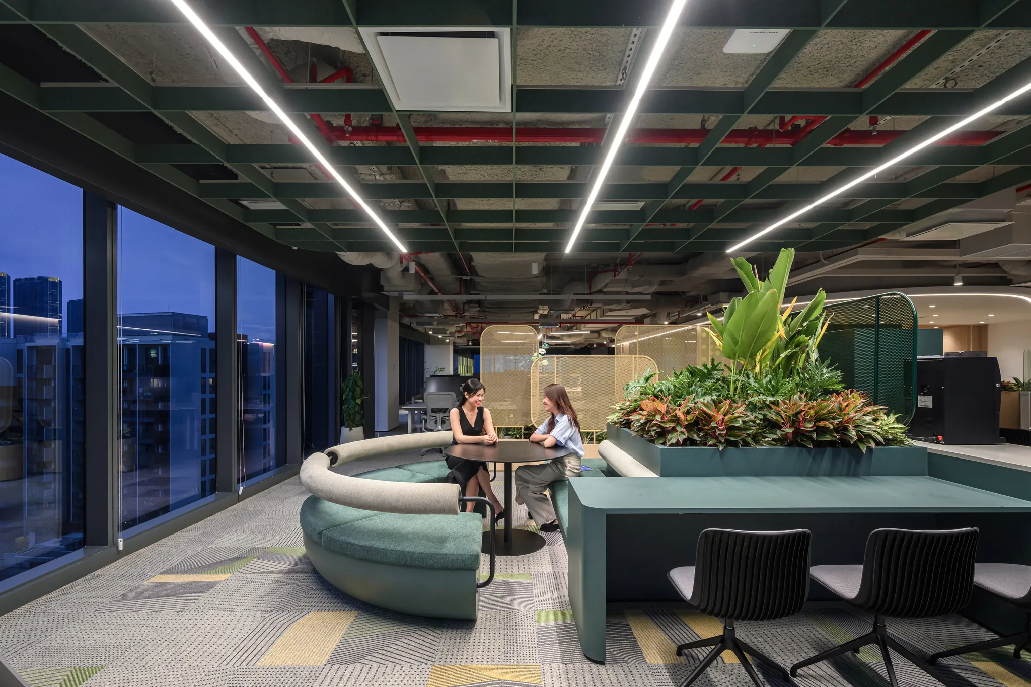 <figcaption>The open working area at NAB Innovation Centre Vietnam features a refreshing green color palette and offers a stunning view of the city skyline.</figcaption>